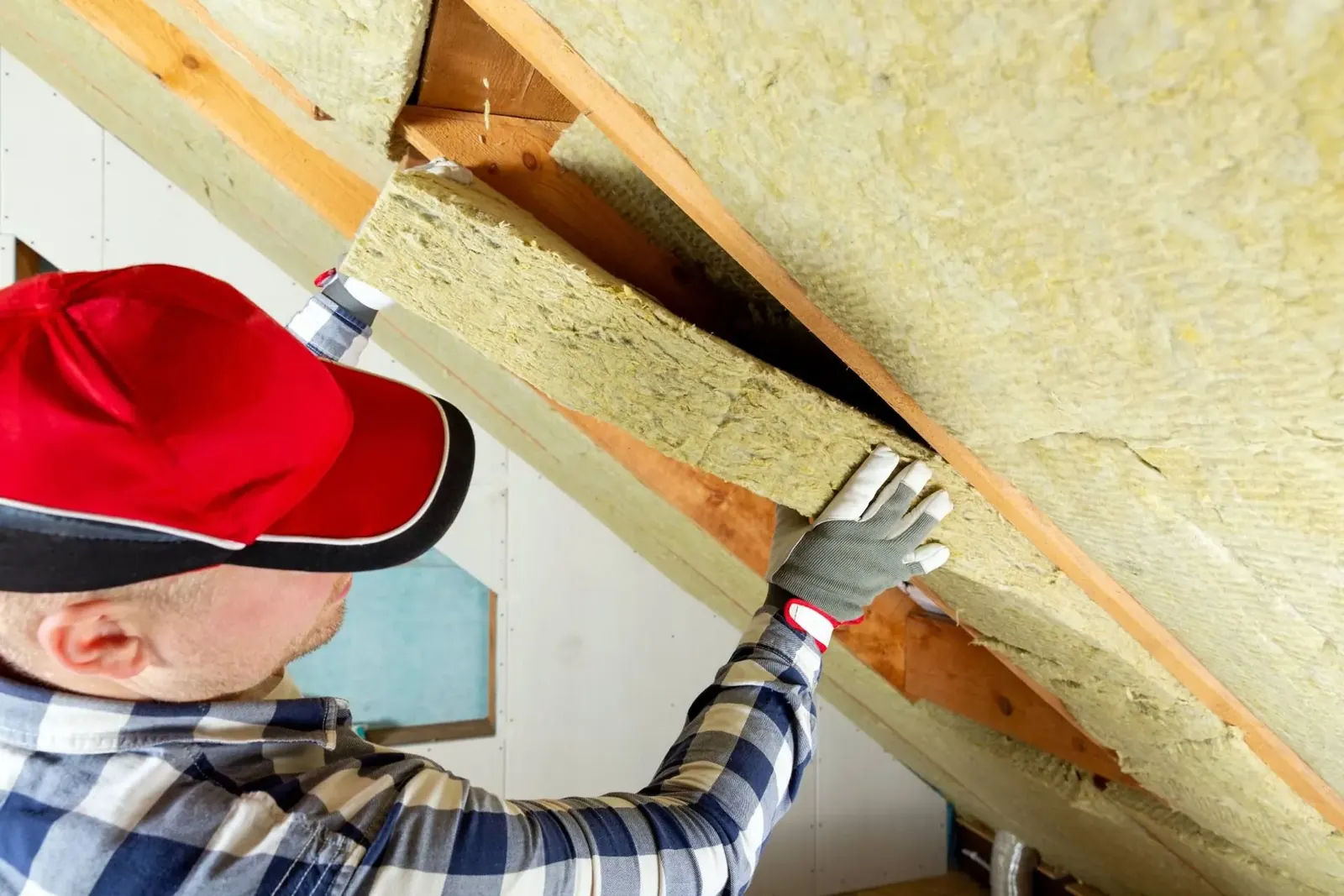Installer fitting insulation between roof rafters