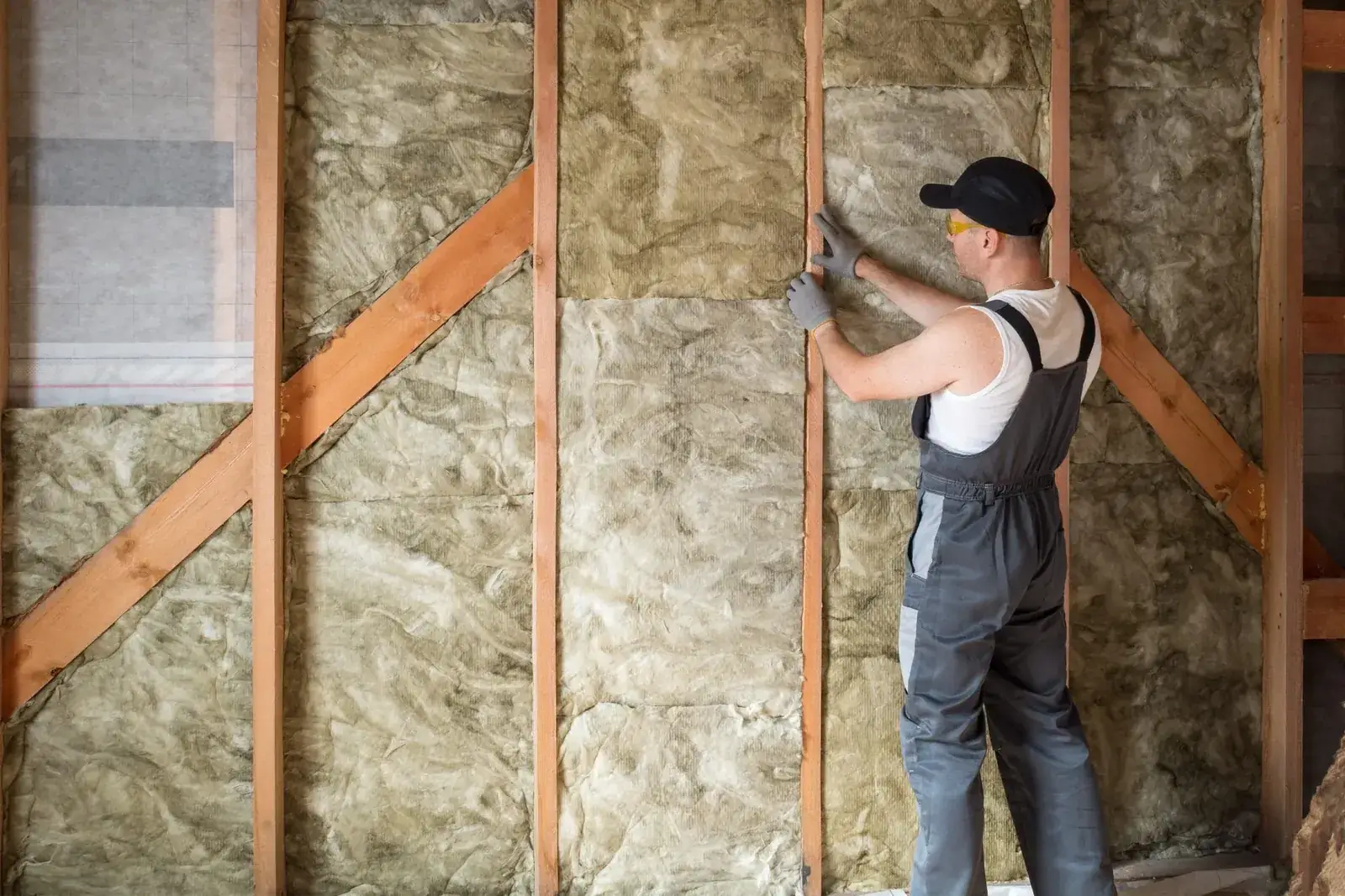 Installer fitting wall batts between timber studs